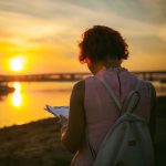 Persona che legge al tramonto in spiaggia
