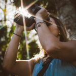 Ragazza che sta utilizzando un binocolo in un bosco