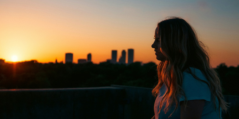 Ragazza guarda l'orizzonte con skyline cittadino alle spalle