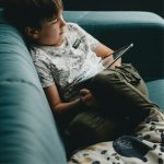 Bambino sul divano che guarda il tablet