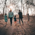 Mamma e papà per mano con i quattro figli al parco in autunno