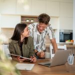Ragazzo e ragazza in ambiente familiare che si consultano davanti ad un computer portatile