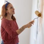 Ragazza che dipinge il muro di casa